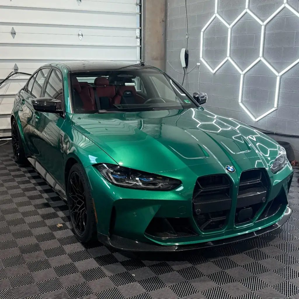 Green BMW M3 with a fresh ceramic coating under shop lights