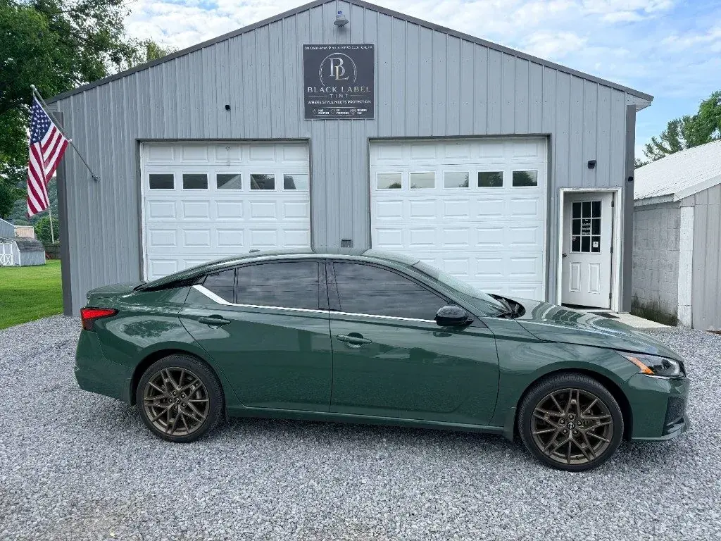 Green Nissan Altima outside Black Label Tint's two-bay shop
