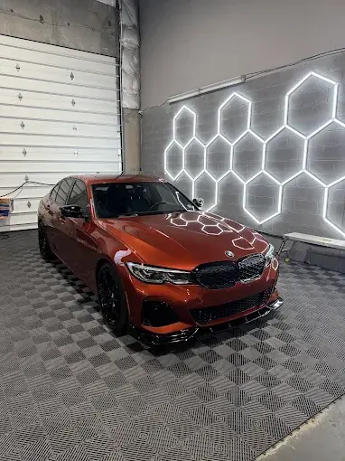Orange BMW with window tint under hexagon shop lights